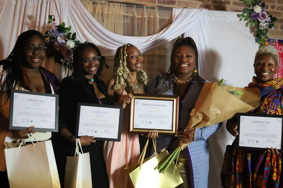 Women holding certificates and flowers, smiling together