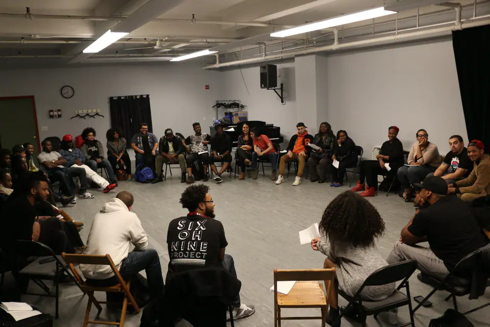 A large circle of young people seated in a workshop room